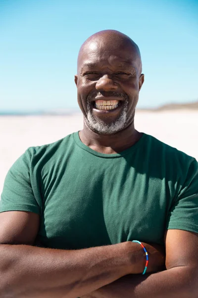 きれいな空に対してビーチで笑顔を交差した腕を持つ自由はげアフリカ系アメリカ人のシニア男性 コピースペース 肖像画 変更されていない ライフスタイル 楽しさと自然コンセプト — ストック写真
