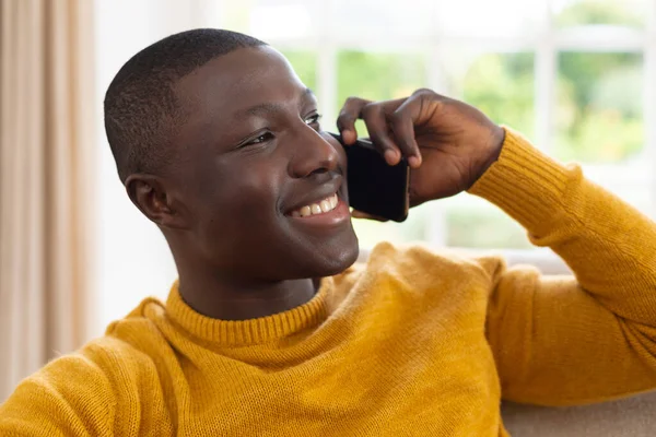 Uśmiechnięty Afrykanin Siedzący Kanapie Mówiący Przez Smartfona Integracja Społeczna Życie — Zdjęcie stockowe