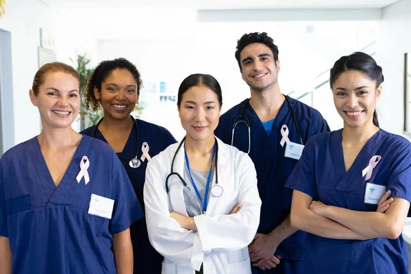 病院の廊下で笑顔癌リボンを身に着けている医療従事者の多様なグループの肖像画 医療サービス — ストック写真