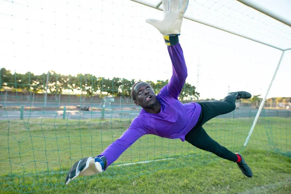 Afrykański Bramkarz Podniesionymi Ramionami Skaczący Łapiący Piłkę Meczu Czystym Niebem — Zdjęcie stockowe