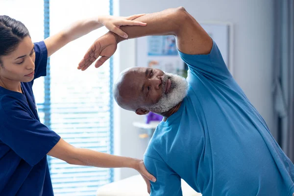 Olika Kvinnliga Sjukgymnast Behandla Äldre Manliga Patienten Med Stretching Motion — Stockfoto