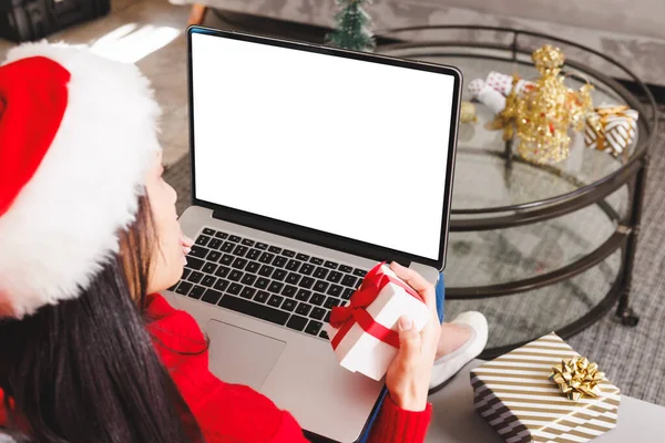 サンタ帽をかぶった乳母の女性は リビングルームのソファに座って コピースペース付きのラップトップを使用しています クリスマスだけで家で質の高い時間を過ごす — ストック写真