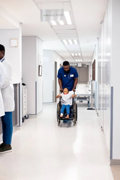 非洲裔美国男性医生将男病人推送到科利多姆的轮椅上 并留有复制空间 医疗和保健服务 — 图库照片