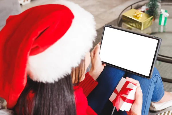 头戴圣诞礼帽 坐在客厅的沙发上 用彩色平板电脑 圣诞时独自在家度过美好的时光 — 图库照片