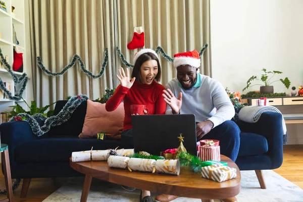 Щаслива Різноманітна Пара Капелюхах Санта Клауса Використовуючи Ноутбук Відеодзвінків Якісний — стокове фото