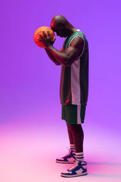 ネオン紫の背景にバスケットボールを持つアフリカ系アメリカ人バスケットボール選手のイメージ スポーツ 競技の概念 — ストック写真