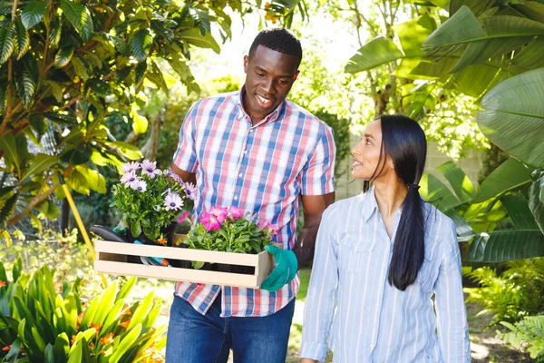 Feliz Casal Diverso Carregando Flores Para Plantar Andando Jardim Falando — Fotografia de Stock