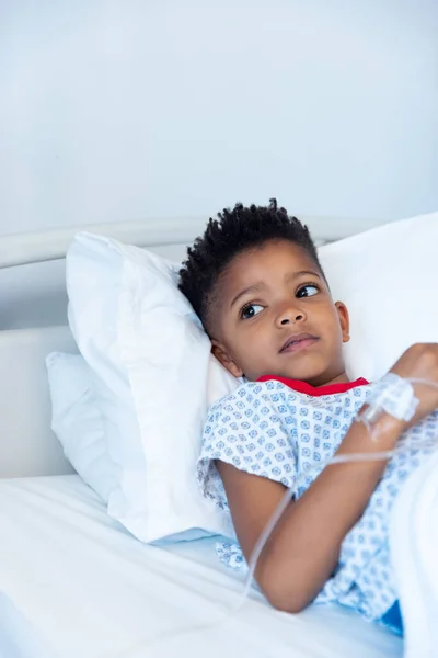 点滴でアフリカ系アメリカ人の少年患者の垂直画像 コピースペースと病院のベッドに横たわっています 医療サービス — ストック写真