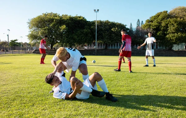 Multiracial Male Player Assisting Injured Teammate Lying Field Getting Match — Stock Photo, Image