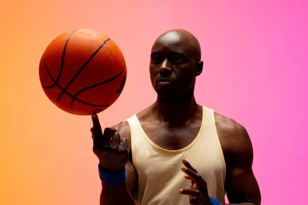 オレンジとピンクの背景でバスケットボールをしているアフリカ系アメリカ人のバスケットボール選手のイメージ スポーツ 競技の概念 — ストック写真