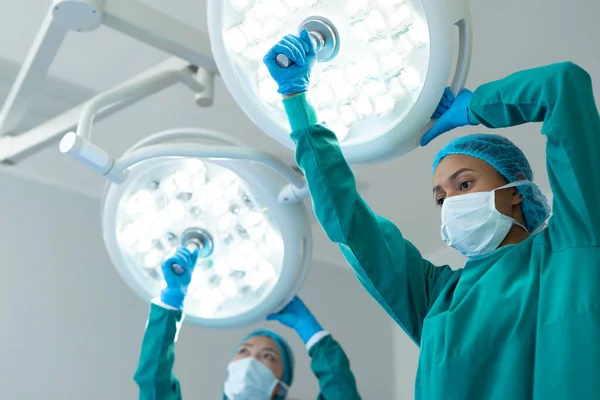 Δύο Διαφορετικές Γυναίκες Χειρουργοί Ρυθμίζουν Φώτα Στο Χειρουργείο Για Λειτουργία — Φωτογραφία Αρχείου