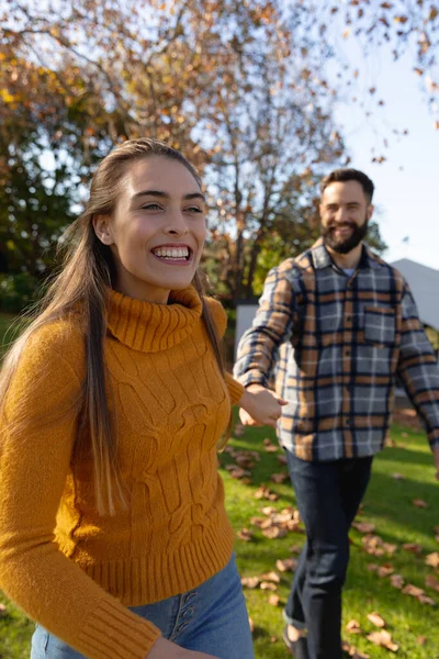 秋の庭を歩く幸せな白人夫婦の垂直画像 一緒に質の高い時間を過ごす — ストック写真