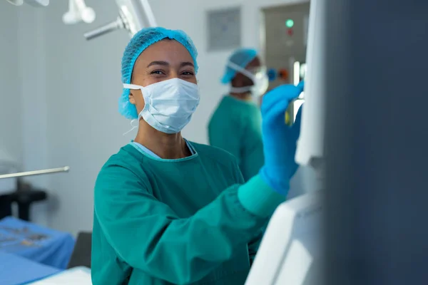 Gülümseyen Çift Irklı Kadın Cerrah Ameliyathanede Bilgisayar Destekli Tıbbi Ekipman — Stok fotoğraf