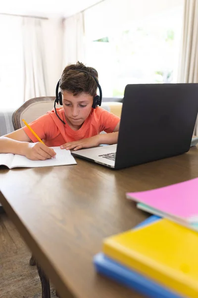 白人男孩在客厅学习和使用笔记本电脑和耳机 家庭教育 远距离教育 — 图库照片