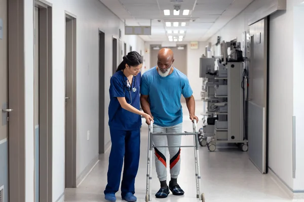 病院の廊下 コピースペースで高齢男性患者が歩行フレームを使用するのを助ける多様な女性医師 医療サービス — ストック写真