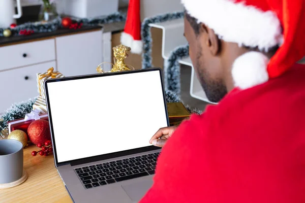 戴着桑塔帽的非裔美国人 使用带有版权空间的笔记本电脑 圣诞时独自在家度过美好的时光 — 图库照片