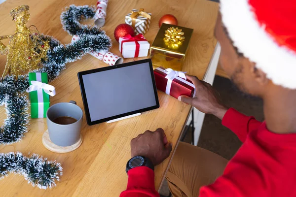 非洲裔美国人戴着桑塔帽 用彩色平板电脑 圣诞时独自在家度过美好的时光 — 图库照片