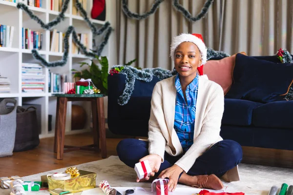 Happy African American Woman Wearing Santa Claus Hat Packing Presents — Stock Photo, Image