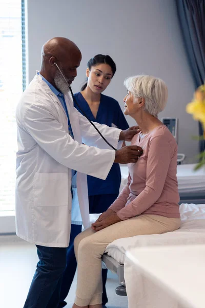 Vertical Diverse Senior Male Doctor Using Stethoscope Examining Senior Female — Stock Photo, Image