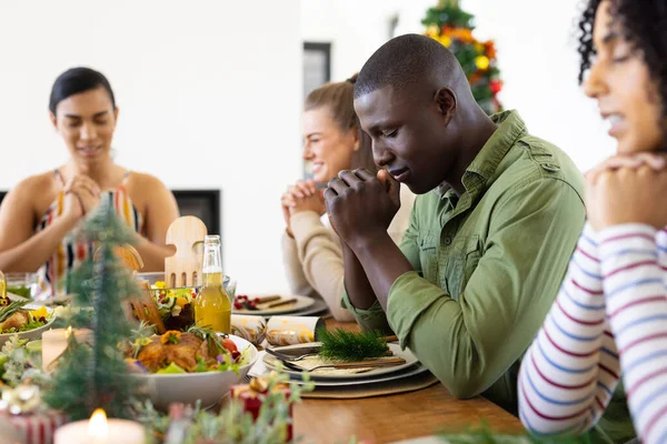Boldog Változatos Barátok Ülnek Asztalnál Imádkoznak Vacsora Előtt Karácsonykor Karácsony — Stock Fotó