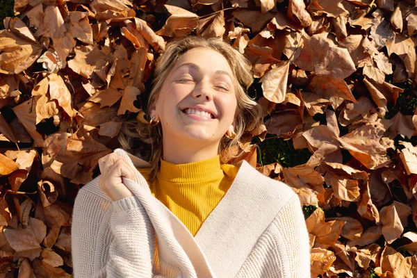 秋の葉の上に横たわる幸せな白人女性と笑顔 質の高い時間を家だけで過ごす — ストック写真