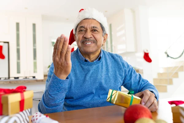 Happy Senior Biracial Man Santa Hat Holding Christmas Present Gesturing — Stock fotografie
