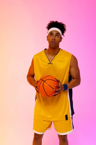 ピンクからオレンジ色の背景にバスケットボールを持つ出生バスケットボール選手のイメージ スポーツ 競技の概念 — ストック写真