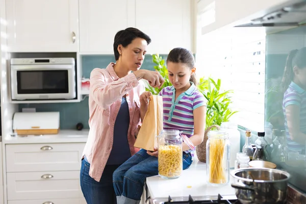在现代化的厨房里 白人母亲和女儿一起打开购物袋 与家人共渡家庭时光 — 图库照片