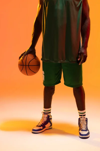 Зображення Середньої Секції Афроамериканського Баскетболу Баскетболом Неоновому Помаранчевому Фоні Спорт — стокове фото