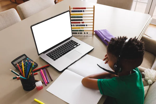幸せなアフリカ系アメリカ人の少年は コピースペースとノートパソコンを使用してテーブルに座っている 家庭生活 子供時代の概念 — ストック写真