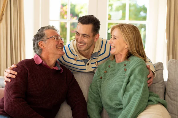 幸せな白人の両親と大人の息子がソファに座って笑顔のイメージ 家族と一緒に質の高い時間を過ごすコンセプト — ストック写真