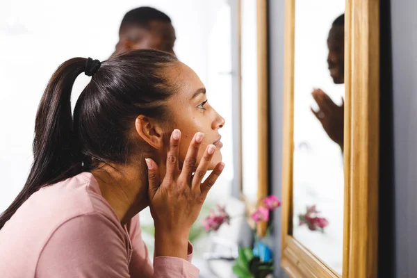 バスルームで幸せな多様なカップルは 女性の鏡の前で顔をクレンジング探している 家庭生活 セルフケアと包括的な概念 — ストック写真