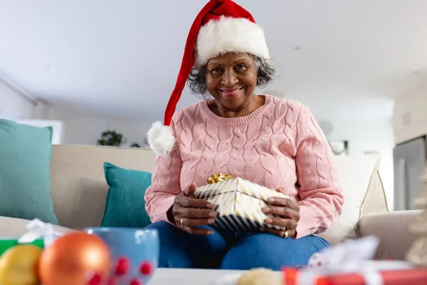 思考上のシニアアフリカ系アメリカ人女性サンタクラスの帽子をかぶっている 技術を使って家で一人で引退しました — ストック写真