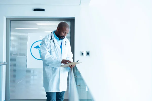 Allvarlig Afrikansk Amerikansk Manlig Läkare Läser Anteckningar Sjukhuskorridoren Med Kopieringsutrymme — Stockfoto