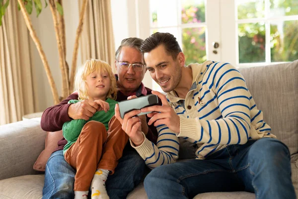 三代快乐的高加索男人坐在沙发上 用智能手机 家庭与共同度过美好时光的概念 — 图库照片