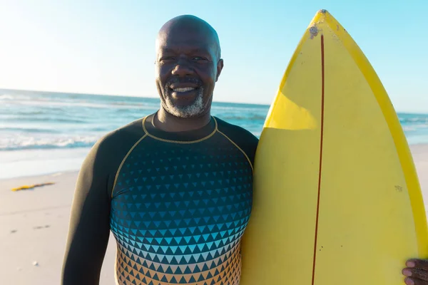 面带微笑的非洲裔美国秃头老人 黄色的冲浪板映衬着大海和晴朗的天空 复制空间 水上运动 — 图库照片