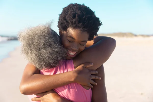 非洲裔美国老年妇女在蓝天的海滩上拥抱幸福的小女儿的后视镜 复制空间 不变的 家庭的 享受和自然的概念 — 图库照片