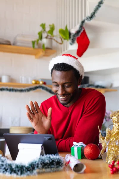 快乐的非洲裔美国人戴着圣塔帽 用平板电脑进行视频通话 圣诞时独自在家度过美好的时光 — 图库照片