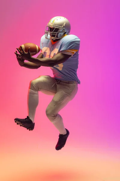 Amerykański Amerykański Futbolista Trzymający Piłkę Neonowym Różowym Oświetleniem Sport Ruch — Zdjęcie stockowe