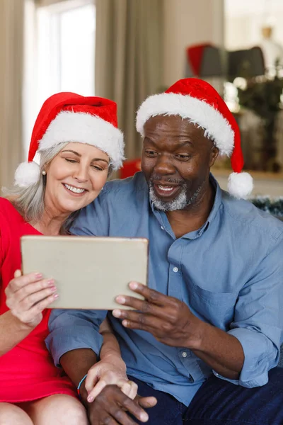 Szczęśliwa Para Seniorów Kapeluszami Mikołaja Pomocą Tabletu Spędzanie Czasu Święta — Zdjęcie stockowe
