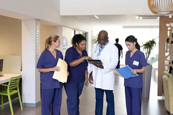 Různorodá Skupina Zdravotnických Pracovníků Tabletami Papírováním Diskutující Nemocniční Chodbě Nemocniční — Stock fotografie