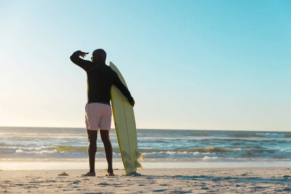 Tylny Widok Afrykańskiego Starszego Pana Deską Surfingową Stojącego Plaży Patrzącego — Zdjęcie stockowe