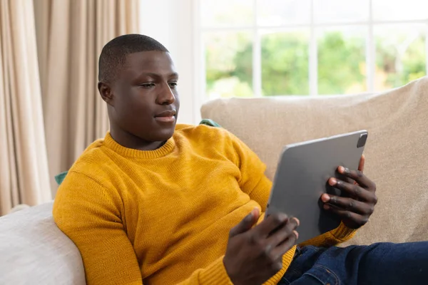Gelukkig Afrikaans Amerikaanse Man Liggend Bank Thuis Tablet Kijken Inclusiviteit — Stockfoto