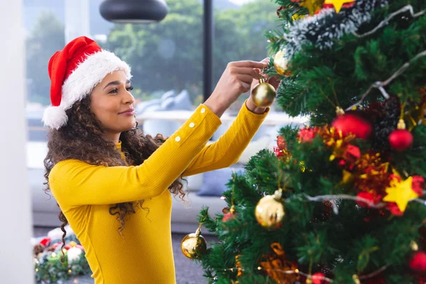 幸せなアフリカ系アメリカ人の女性サンタの帽子をかぶって リビングルームでクリスマスツリーを飾る 一緒にクリスマスに質の高い時間を過ごす — ストック写真