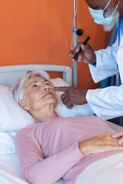 不同的高级男医生用笔灯检查老年女病人的眼睛 复制空间 医疗和保健服务 — 图库照片