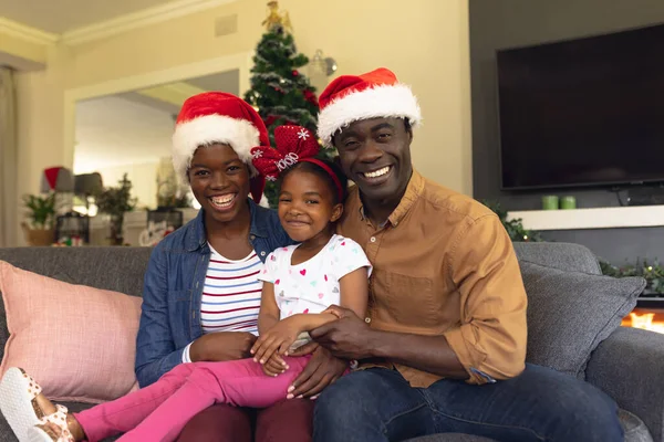坐在沙发上戴圣爪帽的非裔美国人家庭 圣诞节 家庭时间和庆祝概念 — 图库照片