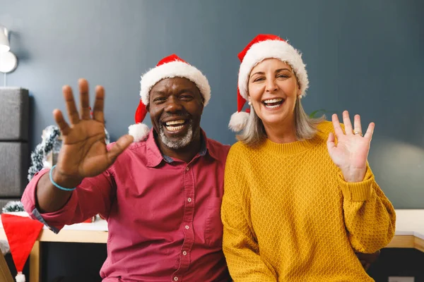 Szczęśliwa Zróżnicowana Para Seniorów Kapeluszach Mikołaja Wykonująca Świąteczną Rozmowę Wideo — Zdjęcie stockowe