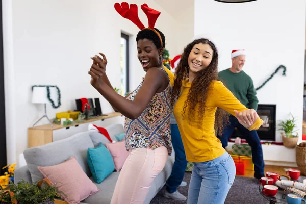 ホームダンスでクリスマスを祝う2人の幸せな多様な女性の友人のイメージ クリスマス お祝い 包括性とライフスタイルの概念 — ストック写真