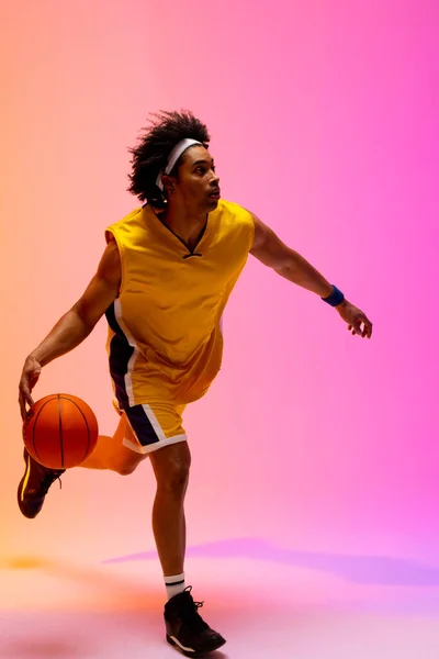 ピンクからオレンジの背景にバスケットボール選手がバスケットボールを跳ねるイメージ スポーツ 競技の概念 — ストック写真
