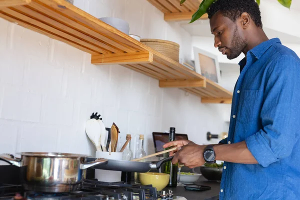 幸せなアフリカ系アメリカ人の男がキッチンや料理の夕食に立っている 自宅だけで質の高い時間を過ごす — ストック写真